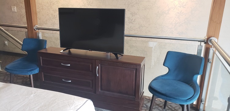 The master bedroom's credenza with large, flat-screen TV and two chairs is shown. Photo by Susan J. Young