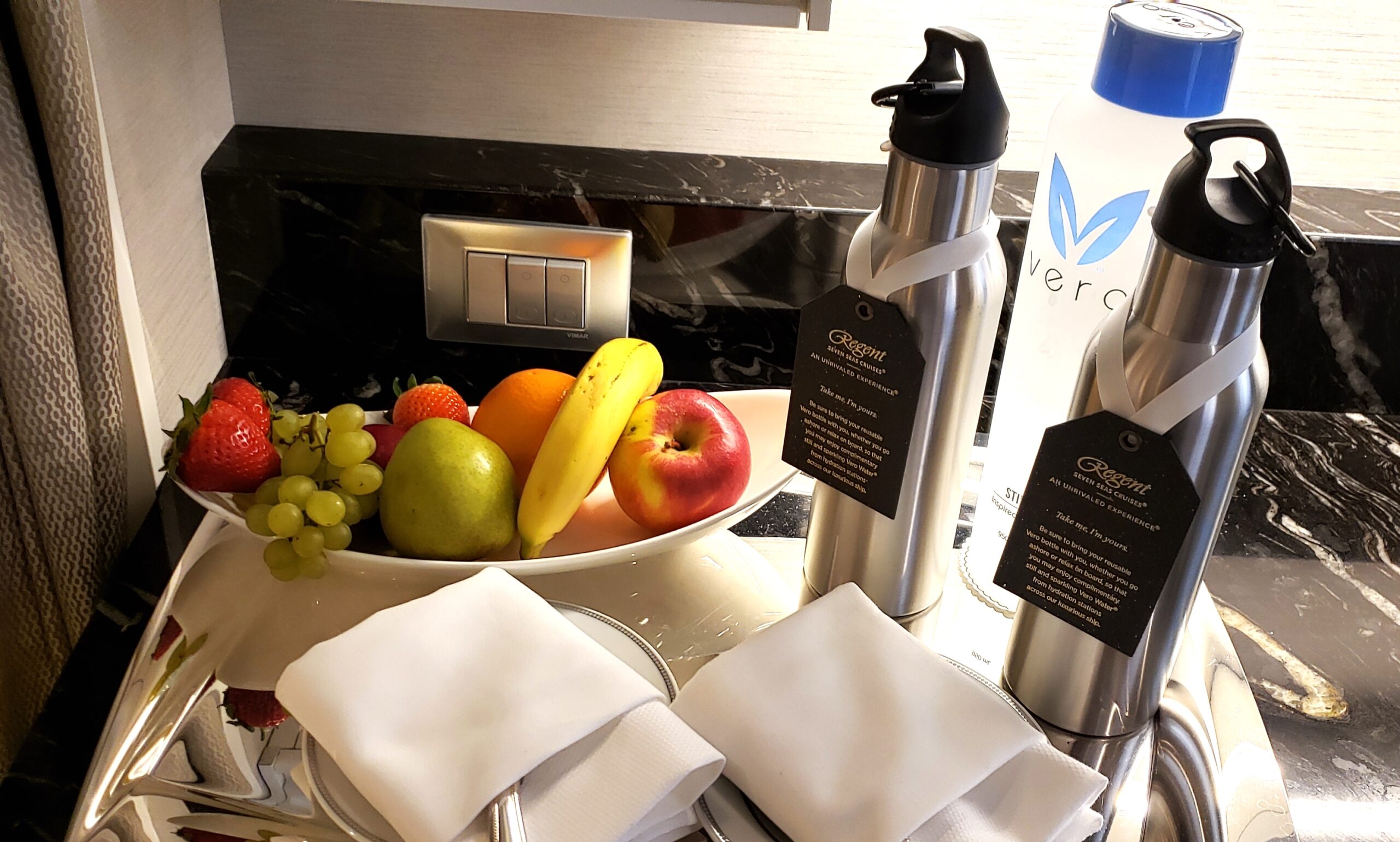 One key step to stay fit on a cruise is to hydrate well and carry a reusable water bottle, often provided by the line. For example, here is fruit and two water bottles provided for guests on Regent Seven Seas Cruises' Seven Seas Splendor. Photo by Susan J. Young.