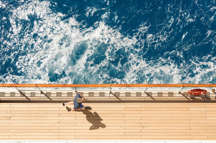 Travelers can cross the Atlantic Ocean in a more relaxing fashion on Cunard's QM2. Shown in this photo, a guest strolls the Promenade Deck and soaks up the fresh air while enjoying ocean views. Photo by Cunard Line. 