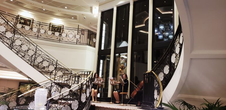 A chamber music trio plays classical music on the atrium's staircase landing as guests board. Photos by Susan J. Young.