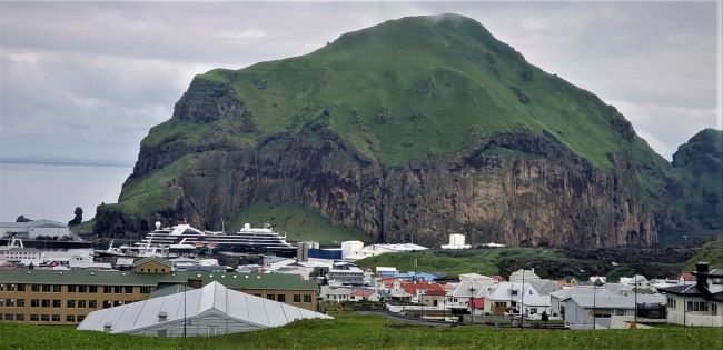 Seabourn Venture is docked in Heimaey's harbor. Volcanic mountains tower over one side of the channel. Photo by Susan J. Young.
