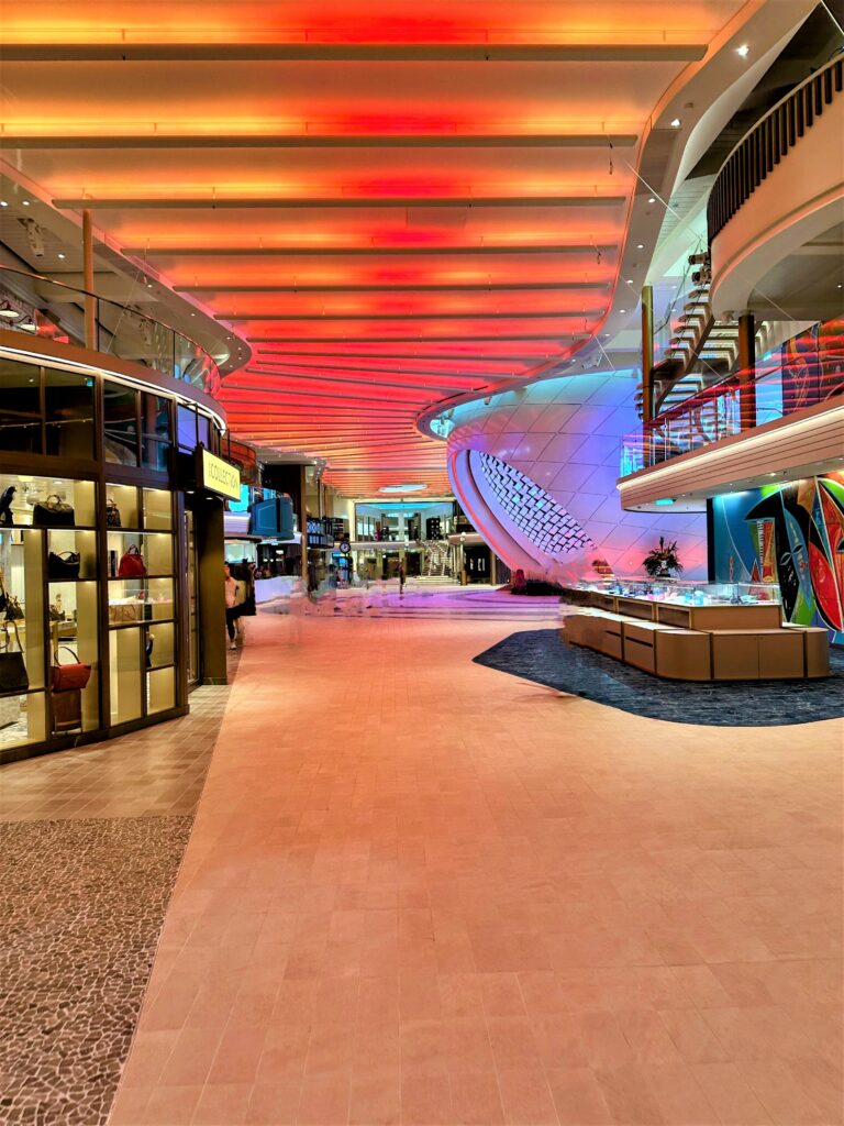 Icon of the Seas' Royal Promenade on Deck 5 with a shop to the left and The Pearl in the distance. Photo by Shelby Steudle.